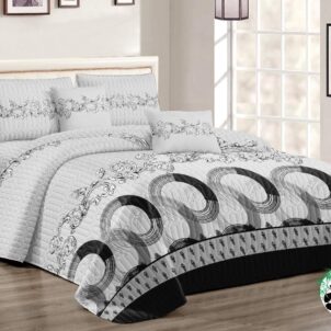 The neatly made bed features a white and gray comforter with circular patterns, part of the 5 Piece Quilt Set available in Queen-King size. Arranged against the headboard are 2x continental pillowcases and 2x standard pillowcases. Natural light floods in through a large window, illuminating the room beautifully.