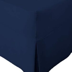 Close-up of a corner section of a navy blue bed skirt with a tailored design. Part of a combo set, the bed skirt features a neat pleat at the corner, draping smoothly to the floor. The fabric appears soft and pastel in color.