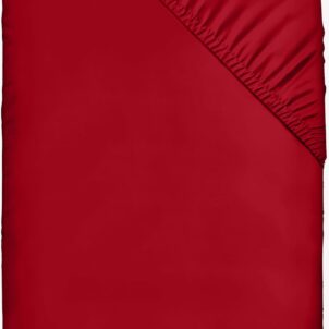 An red fitted sheet is shown spread out. One corner is folded back to display the gathered elastic edging. The material appears smooth and tightly woven, emphasizing its texture and rich, vibrant color.