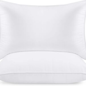 Two white square pillows, one leaning against the other, placed on a white surface. The fabric appears soft and plush, suitable for home decor or bedding.