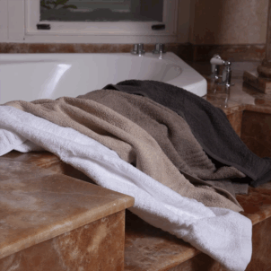 Luxury 500gsm bath towel made from combed cotton yarn in a warp knit construction, offering a refined balance of softness, durability, and absorbency. Available in elegant shades of white, taupe, grey, and pebble.