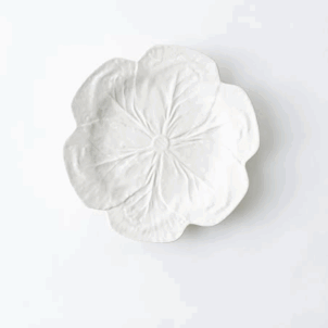 White small dessert or saucer plate designed in the shape of a cabbage leaf, adding a touch of organic charm and texture to the presentation.